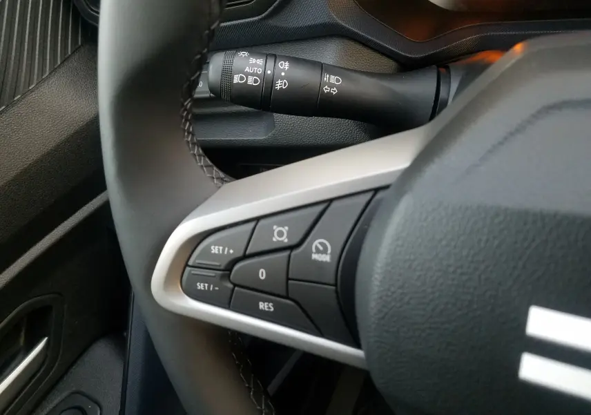Gros plan sur les commandes au volant à gauche du Dacia Duster gris schiste 2025, avec les boutons de régulateur de vitesse.