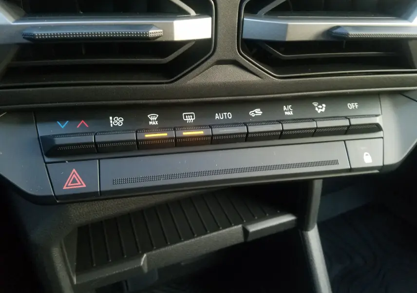 Panneau de commandes de climatisation automatique du Dacia Duster gris schiste, avec boutons rétroéclairés et aérateurs noirs.