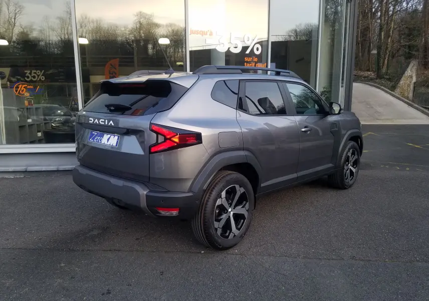 Vue 3/4 arrière droite du Dacia Duster 2025 gris schiste avec feux arrière LED et jantes alliage noires.