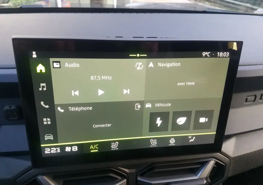 Écran tactile central du tableau de bord du Dacia Duster 2025, affichant radio, navigation et climatisation.
