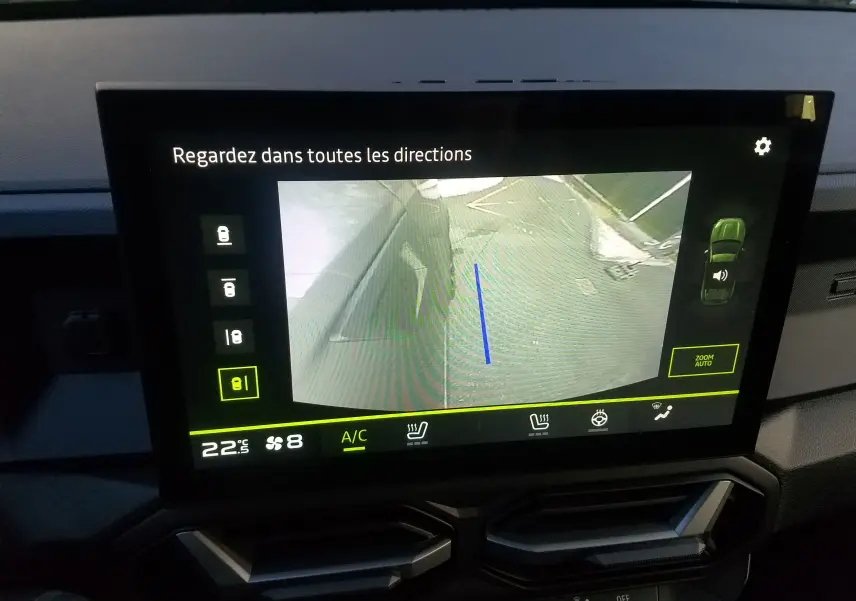 Vue de la caméra de recul affichée sur l'écran intérieur du Dacia Duster gris schiste, avec guidage de trajectoire bleu.