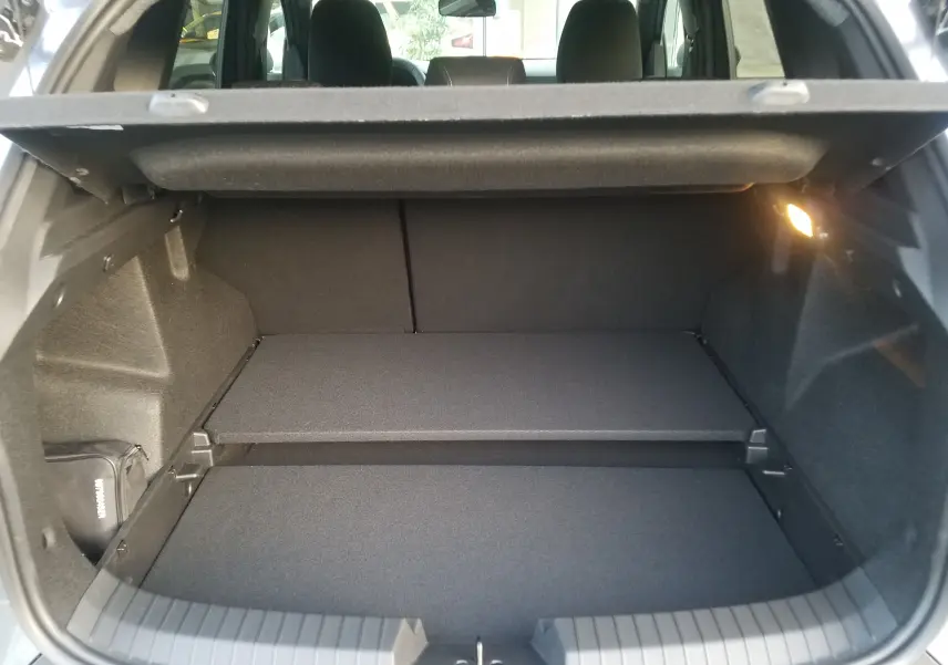 Coffre ouvert du Dacia Duster 2025 gris schiste, vue arrière montrant un espace de rangement modulable et éclairé.