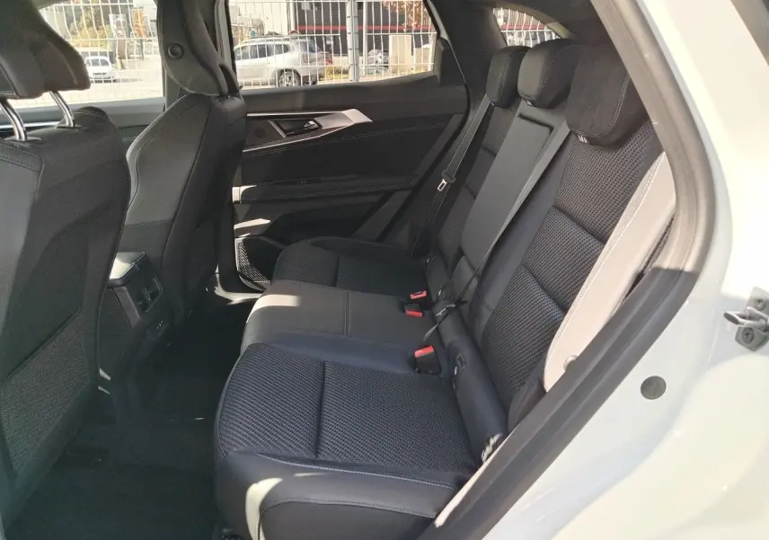 Vue côté droit de l'habitacle arrière du Renault Austral blanc nacré, montrant les sièges noirs en tissu et cuir.