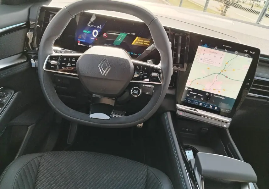 Vue intérieure centrée sur le volant et tableau de bord numérique du Renault Austral E-Tech blanc nacré, avec écran tactile vertical.