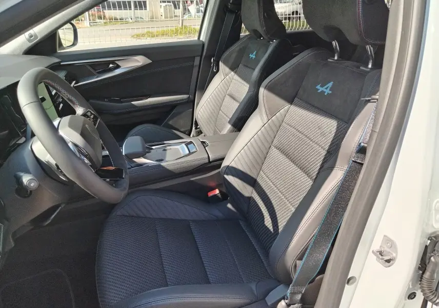 Vue intérieure côté conducteur du Renault Austral E-Tech blanc nacré, sièges sport noirs avec logo Alpine bleu brodé.