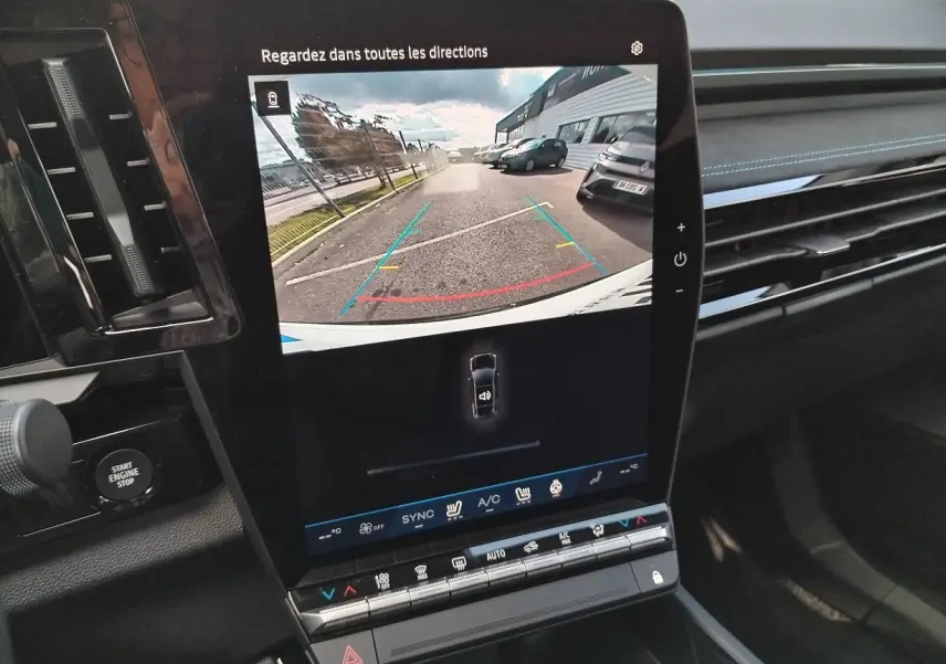 Vue rapprochée de l'écran central tactile du Renault Austral blanc nacré, affichant la caméra de recul avec guidage coloré.