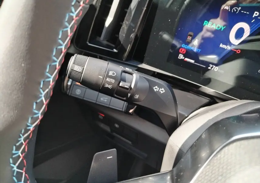 Gros plan sur la manette de clignotant et le tableau de bord digital du Renault Austral blanc nacré 2025.