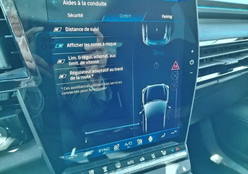 Écran tactile central du Renault Austral E-Tech blanc nacré, affichant les aides à la conduite et la climatisation.