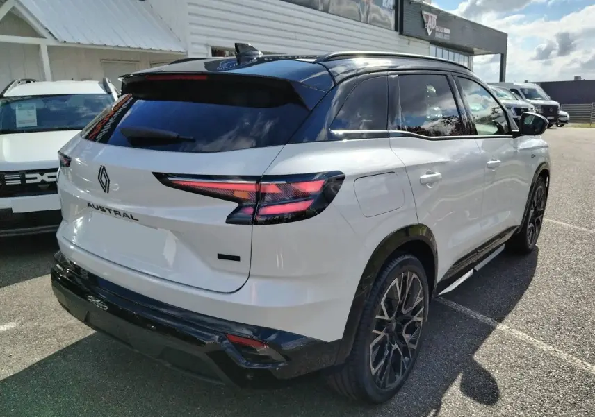 Vue 3/4 arrière droite d'un Renault Austral blanc nacré avec toit noir et jantes noires au design sportif.
