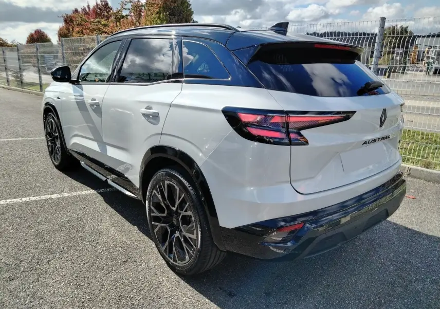 Vue 3/4 arrière droite du Renault Austral blanc nacré avec toit noir et jantes noires distinctives.