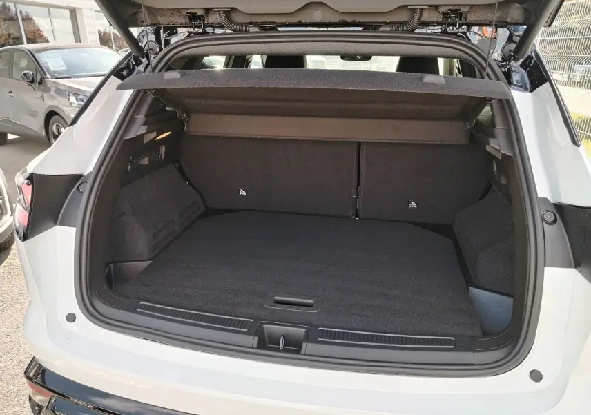 Coffre ouvert vu de l'arrière d'un Renault Austral blanc nacré avec toit noir, montrant un espace de chargement spacieux.