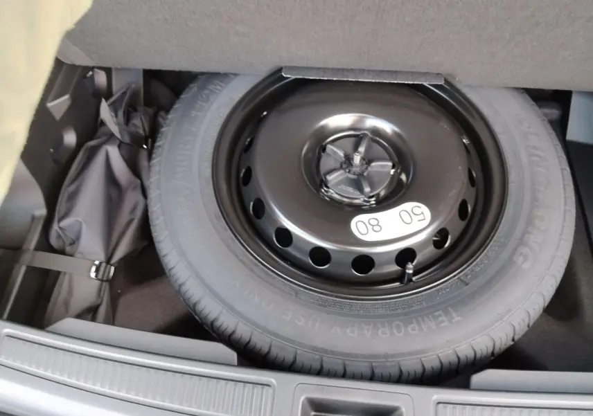 Roue de secours noire en gros plan dans le coffre du Renault Austral E-Tech Full Hybrid 2025 blanc nacré avec toit noir.