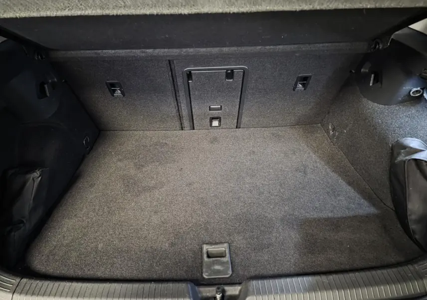 Coffre spacieux et propre de la Volkswagen Golf 1.4 eHybrid gris, vue intérieure arrière avec tapis gris.