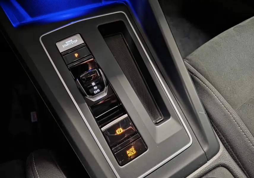 Vue rapprochée de la console centrale de la Volkswagen Golf gris, montrant la commande de boîte auto DSG et le frein à main électronique.