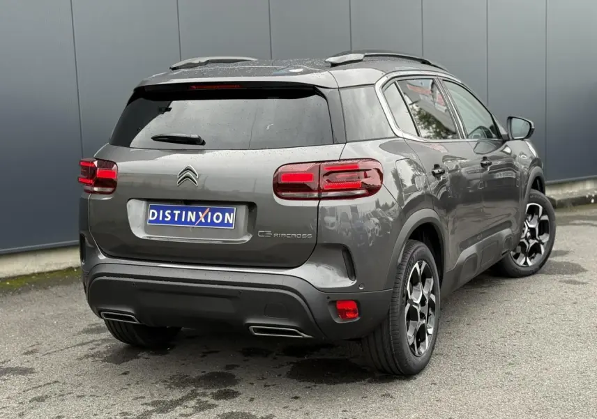 Vue 3/4 arrière droite d'un Citroën C5 Aircross gris Platinium avec toit noir et jantes alliage bi-ton.