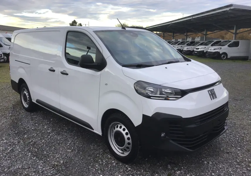 Fiat Scudo Fourgon blanc en 3/4 avant droit, avec pare-chocs noir et jantes acier, sur parking extérieur.