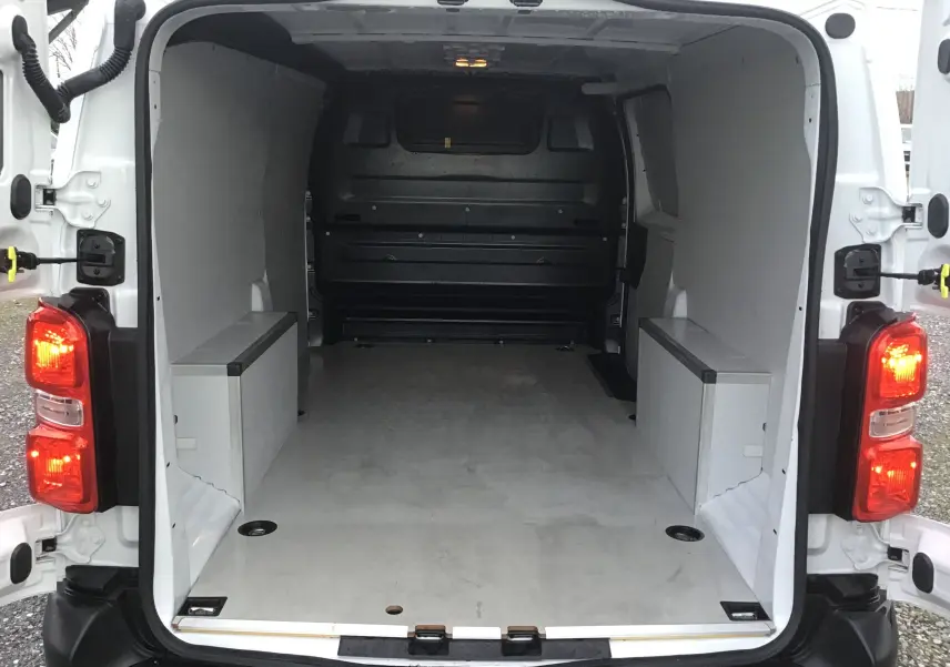 Vue arrière du fourgon blanc FIAT Scudo XL 2024, espace de chargement vide avec parois et plancher protégés.