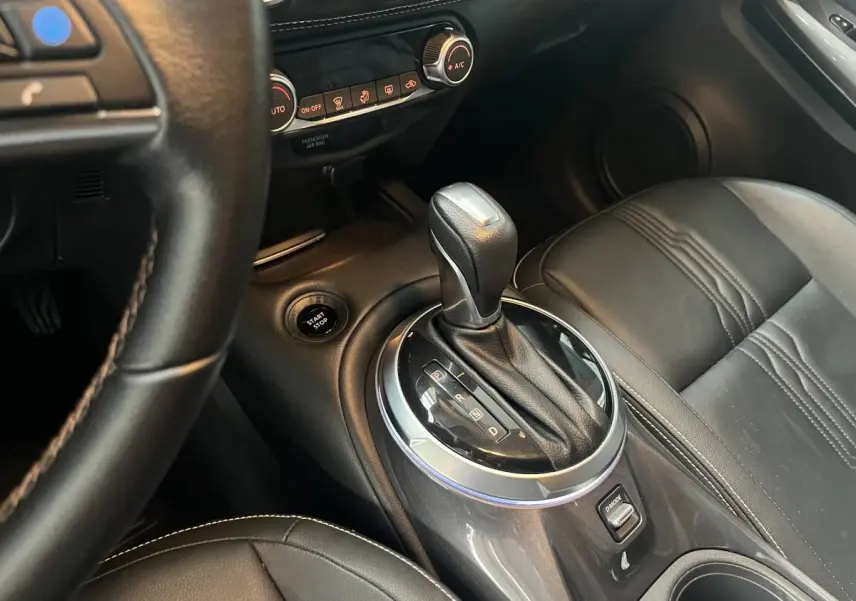 Vue intérieure rapprochée du levier de vitesse automatique et siège en cuir noir du Nissan Juke Hybrid 2024 côté droit.