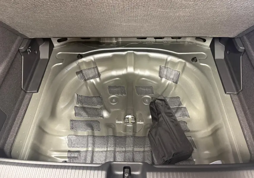 Coffre ouvert d’un Audi Q2 35 TFSI 150 S tronic 7 S line 2026, montrant le logement métallique de la roue de secours.