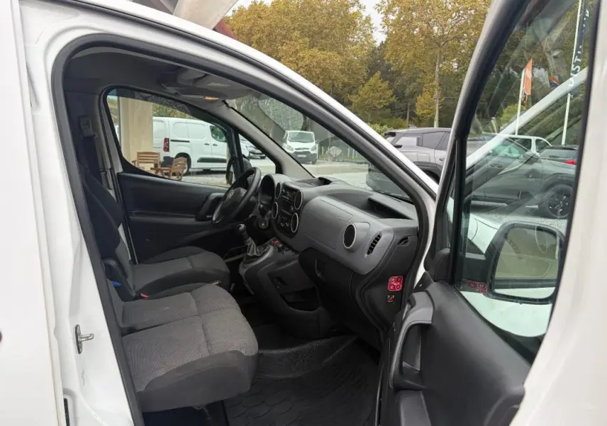 Vue intérieure côté conducteur du Citroën Berlingo blanc 2018, montrant les sièges, le tableau de bord et la boîte manuelle.