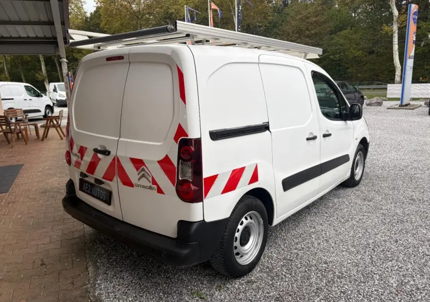 Vue 3/4 arrière droite d’un Citroën Berlingo blanc 2018 avec marquages rouges réfléchissants et galerie sur le toit.