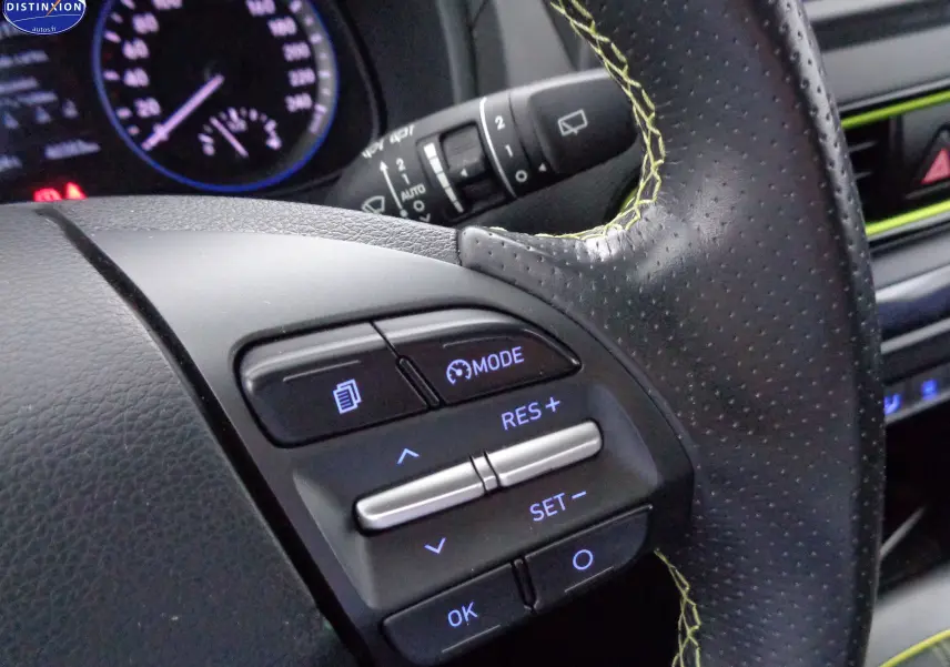 Gros plan sur les commandes de régulateur de vitesse du volant en cuir noir avec surpiqûres jaunes du Hyundai Kona 2019.