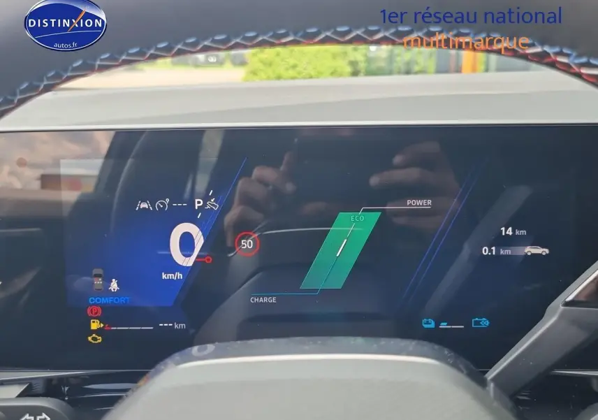 Tableau de bord digital du Renault Austral 2025 en mode hybride, affichage vitesse et charge batterie visible.