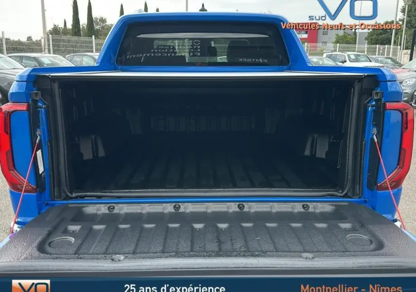 Coffre ouvert en vue arrière d'un Volkswagen Amarok Simple Cabine bleu 2025 avec benne spacieuse et ridelle abaissée.