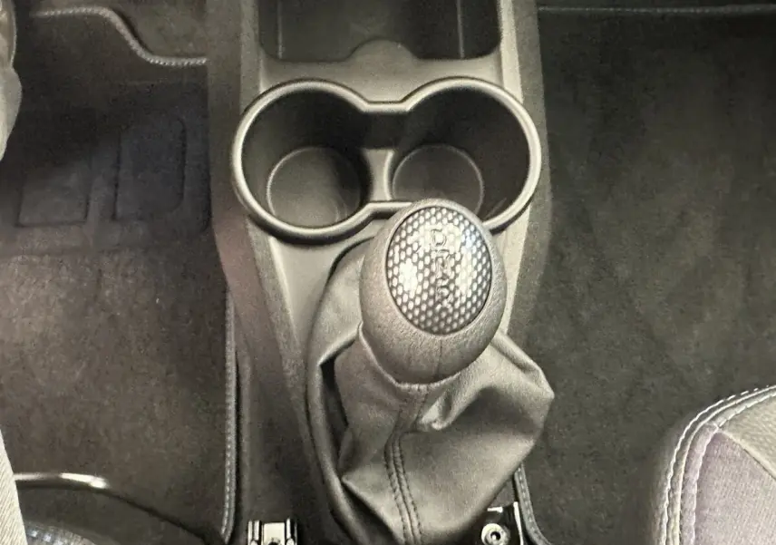 Gros plan sur le levier de vitesses automatique et porte-gobelets au centre de l’habitacle d’une Aixam Ambition blanche.