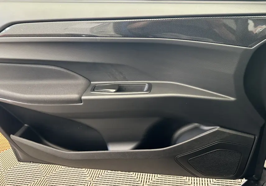 Vue intérieure du panneau de porte côté conducteur de l'AIXAM AMBITION 0.5 CITY GTO blanc avec poignée argentée et haut-parleur intégré.