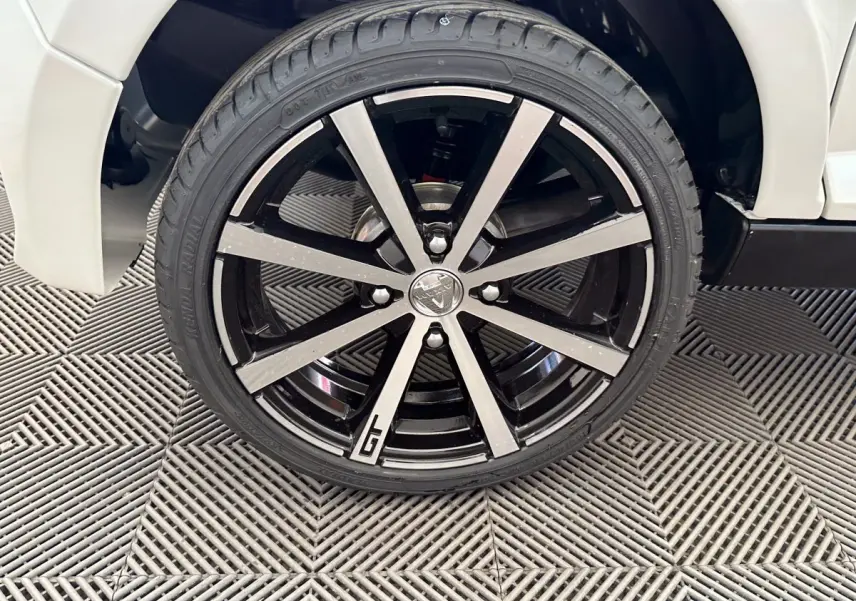 Gros plan sur la roue avant droite de l'AIXAM AMBITION 0.5 CITY GTO blanche, avec jante noire et argentée marquée GTO.