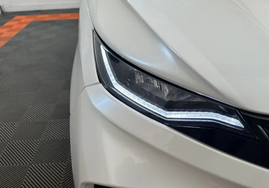 Gros plan sur le phare avant gauche blanc de l'AIXAM AMBITION 0.5 CITY GTO 2026 avec éclairage LED allumé.