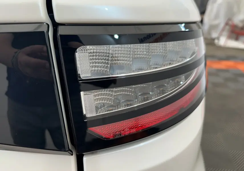 Gros plan sur le feu arrière droit blanc et noir de l'AIXAM AMBITION 0.5 CITY GTO 2026 avec détails lumineux rouges et transparents.