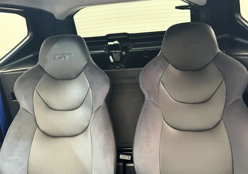 Vue intérieure sur les sièges avant gris avec logo GT, arrière noir et partie vitrée du toit visible.