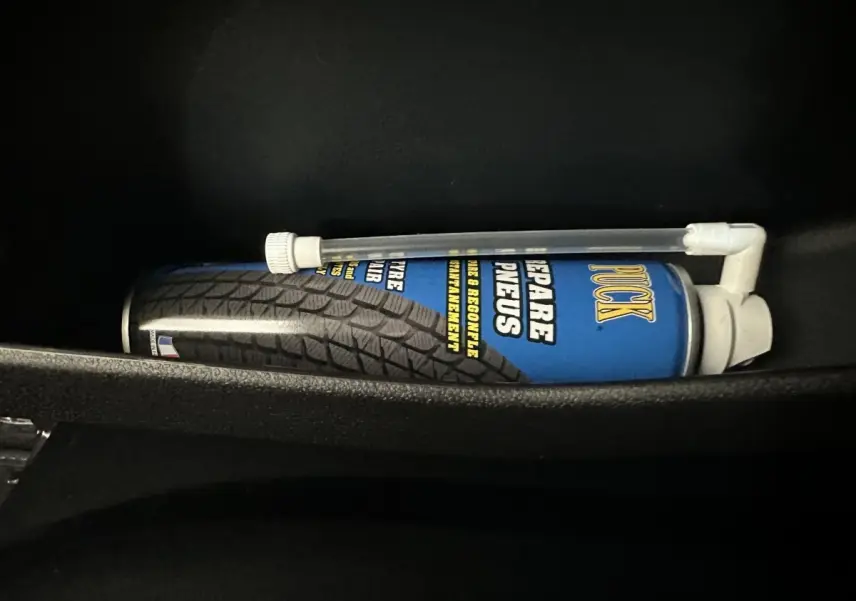 Image intérieure montrant une bombe de réparation pneus rangée dans le compartiment d'une Aixam Ambition 0.5 City GTO blanche.