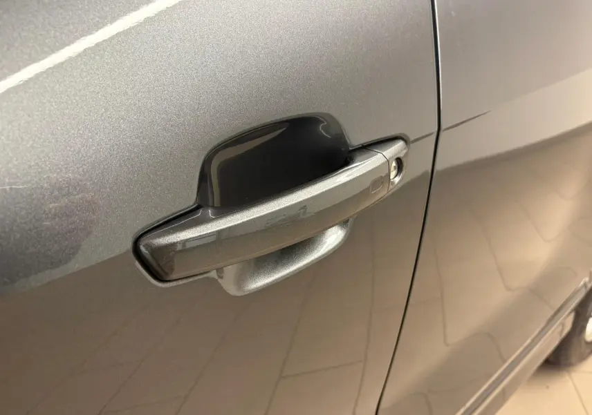 Gros plan sur la poignée de porte côté droit de l'Audi Q2 35 TFSI gris Daytona avec peinture métallisée.
