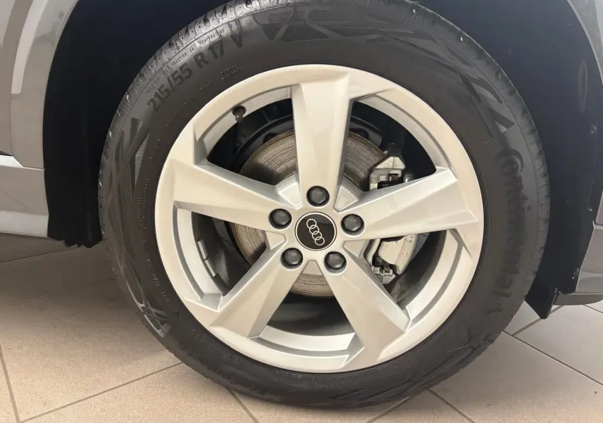 Gros plan sur la roue avant gauche de l'Audi Q2 35 TFSI S Line gris Daytona, mettant en valeur la jante en alliage.