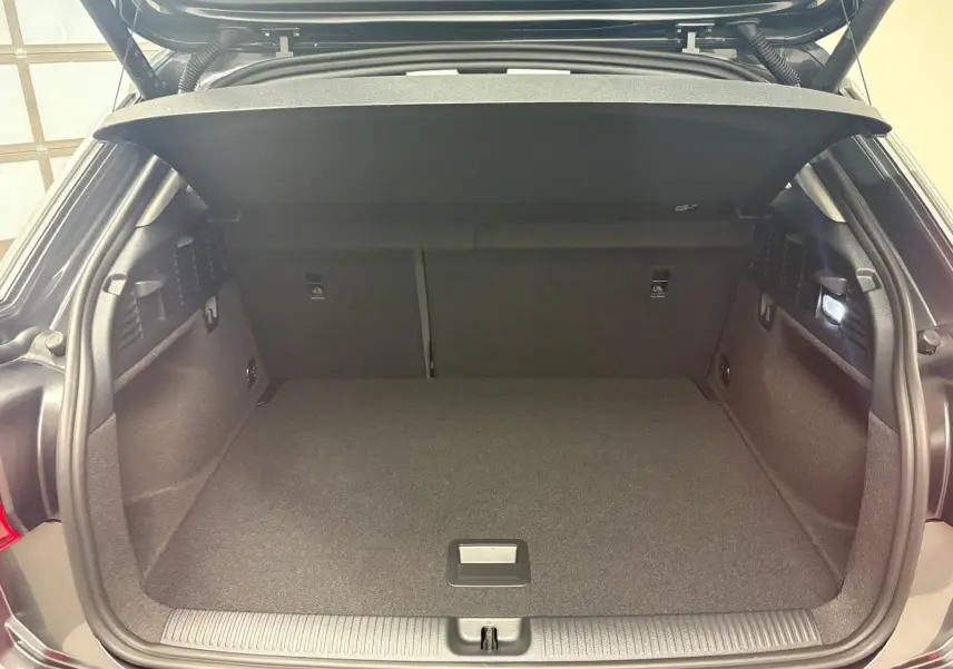 Coffre ouvert vu de l'arrière d'un Audi Q2 gris Daytona, montrant un espace de chargement propre et bien éclairé.