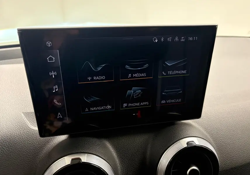 Écran tactile central de l’Audi Q2 35 TFSI S Line 2026, avec commandes multimédias et aérateurs ronds en dessous.