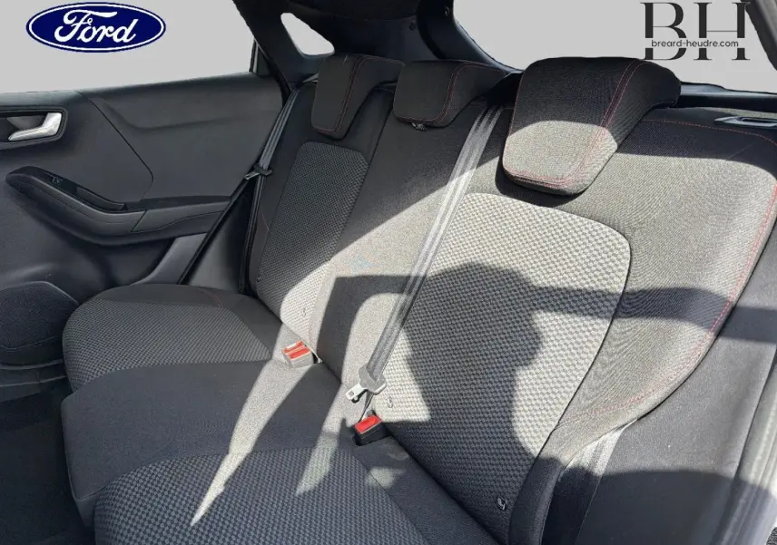 Vue intérieure de la banquette arrière côté gauche du Ford Puma 2024 avec tissu noir et surpiqûres rouges.