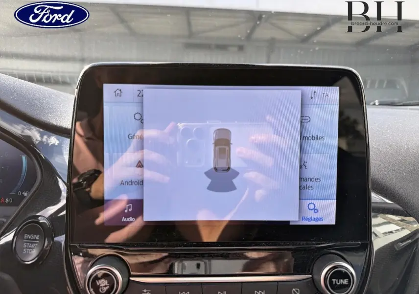 Écran tactile central du Ford Puma 2024 en gros plan, avec affichage du système d’aide au stationnement et bouton start/stop visible.