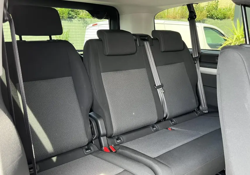 Vue intérieure montrant la banquette arrière en tissu gris et noir du Citroën Spacetourer XL 2024 avec ceintures de sécurité visibles.