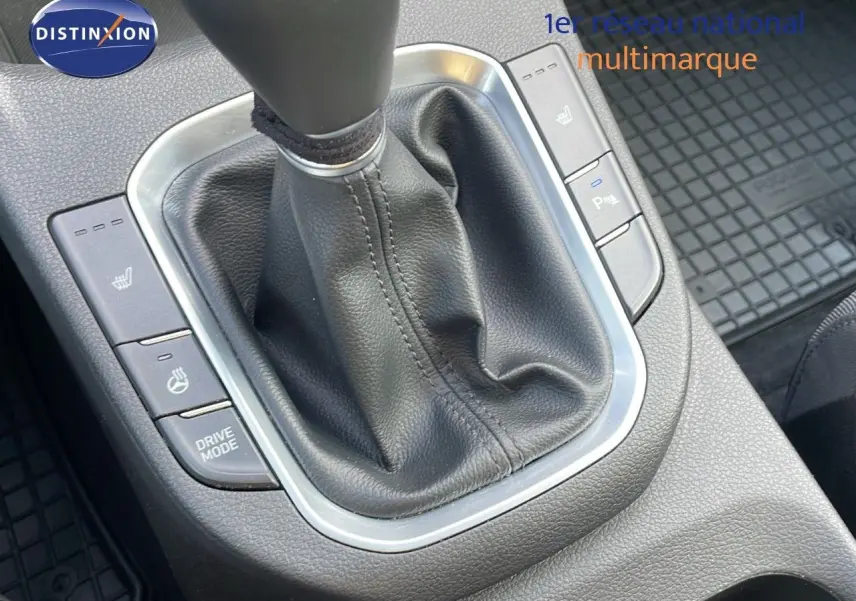 Gros plan sur la console centrale de la Hyundai i30 SW 2024, levier de vitesse manuel en cuir noir et boutons chauffants.