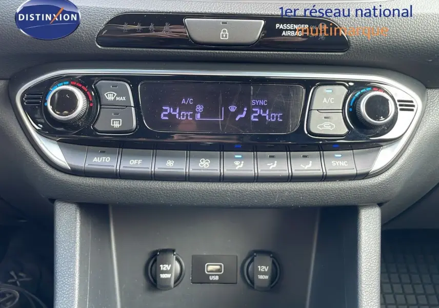 Vue rapprochée de la console centrale de la Hyundai i30 SW 2024, montrant la climatisation digitale et prises USB et 12V.