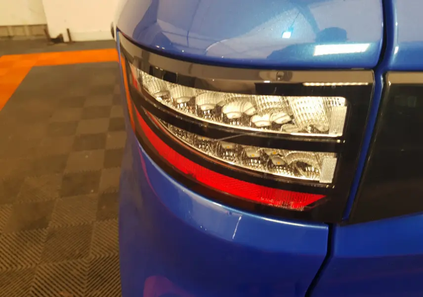 Gros plan sur le feu arrière droit bleu d'une Aixam Ambition 0.5 City Sport 2026 avec finition brillante.