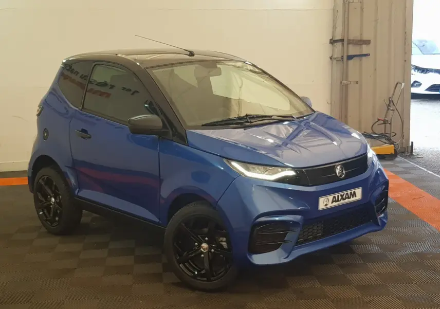 Vue 3/4 avant d'une Aixam Ambition 0.5 City Sport bleu avec jantes noires et rétroviseur caméra côté gauche.