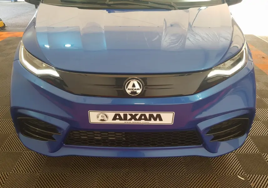 Vue frontale d'une Aixam Ambition 0.5 City Sport bleu avec calandre noire et phares LED allumés.