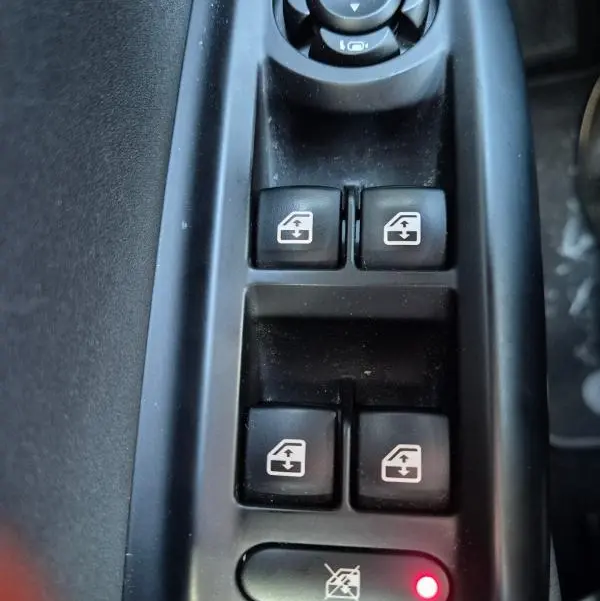 Gros plan sur les commandes de lève-vitres et réglage des rétroviseurs dans l'habitacle noir de l'Alfa Romeo Tonale 2025.