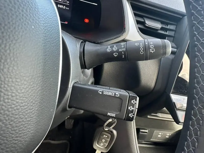 Gros plan sur la colonne de direction noire du Renault Captur 2025 avec commandes de phares et essuie-glace visibles.
