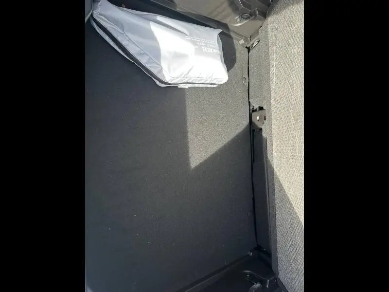 Vue intérieure du coffre du Renault Captur blanc nacré, montrant un rangement avec un sac gris posé sur le tapis noir.